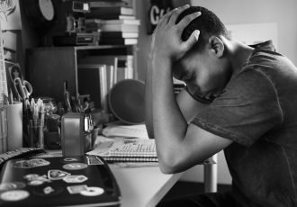 Teenage boy in a bedroom doing work stressed out and frustrated